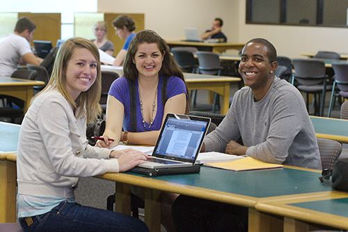 three students sit around laptop